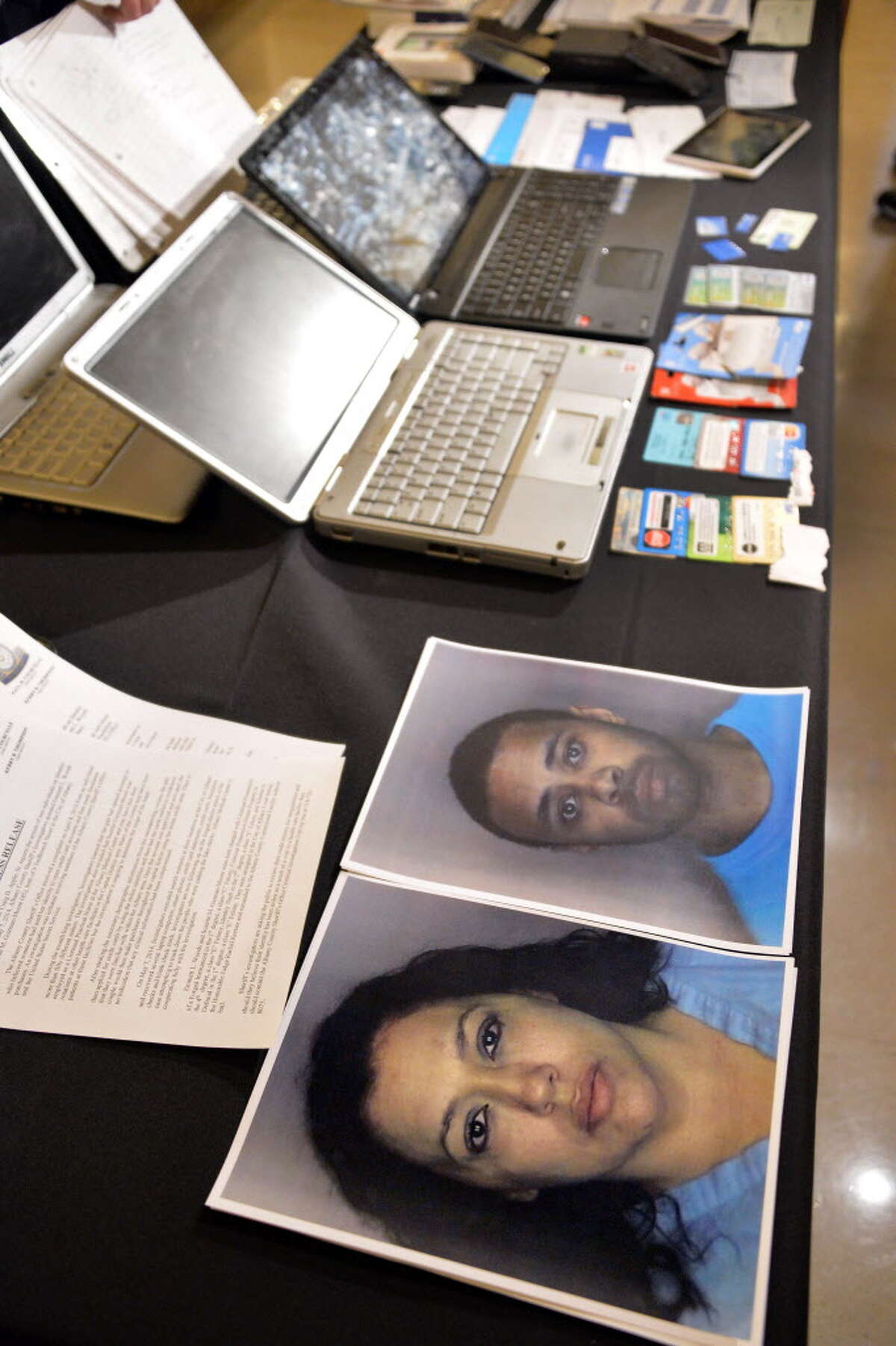Albany Co. Sheriff Dept. photos of Suzette M. Guzman-Moore, bottom, and Emmett L. Woods on a table full of evidence at the announcement of their arrest on Identity Theft charges during at news conference Thursday May 8, 2014, in Albany, NY. (John Carl D'Annibale / Times Union)