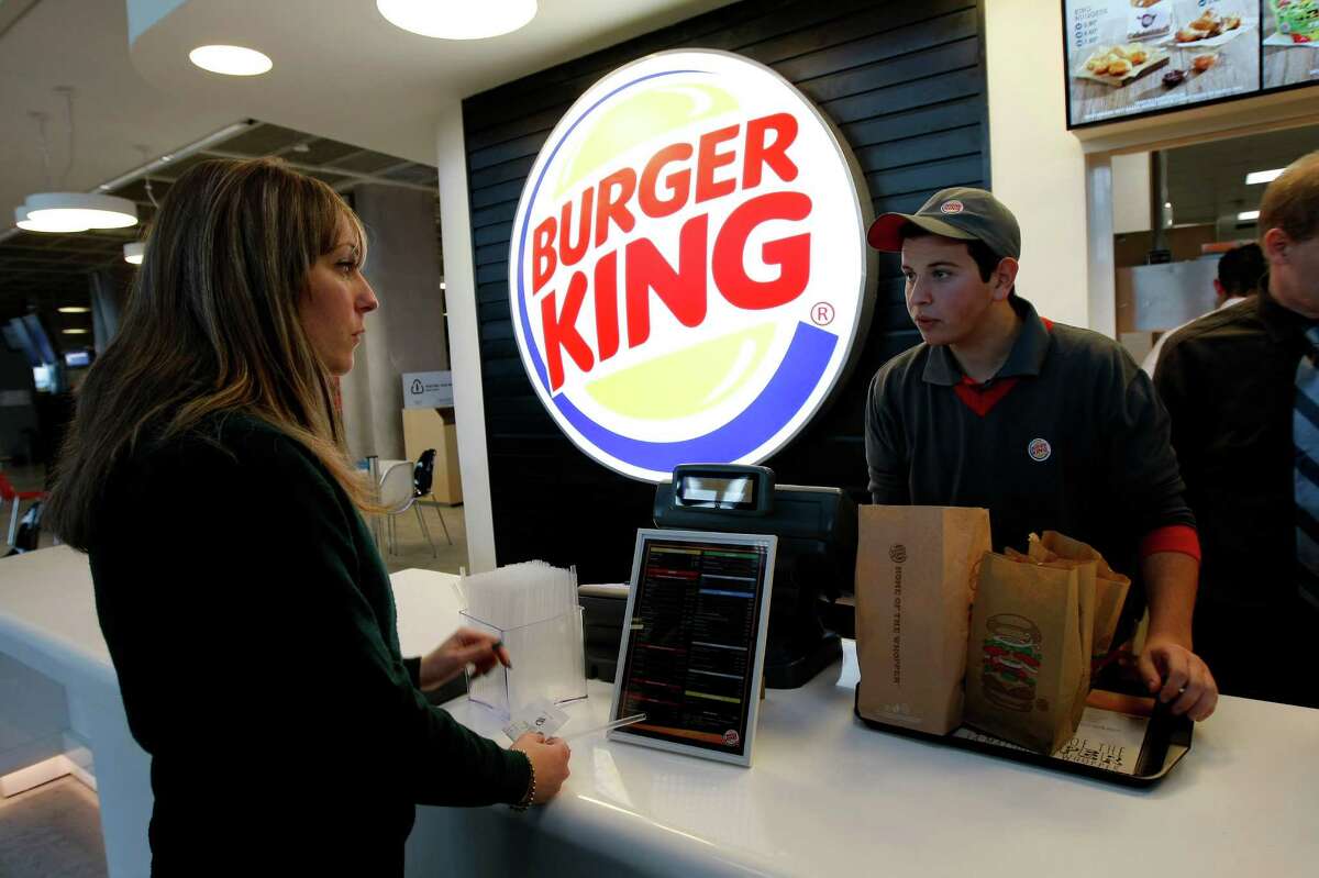 FILE - In a Saturday, Dec. 22, 2012 file photo, a customer purchases a meal at a Burger King restaurant in Marseille-Provence airport, in Marignane, France. Burger King is in talks to buy Tim Hortons in hopes of creating a new, publicly traded company with its headquarters in Canada. (AP Photo/Claude Paris, File)