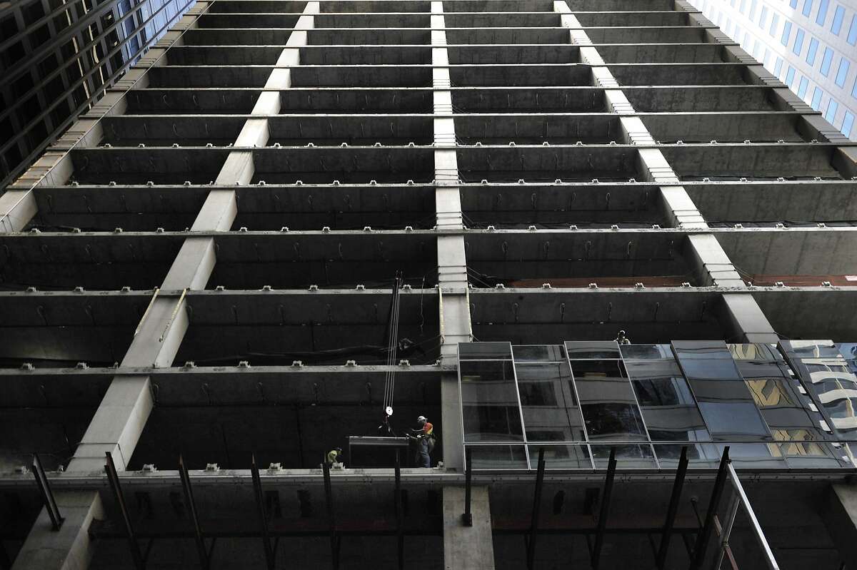 Construction workers install window panels on 350 mission on August 26, 2014 in San Francisco, CA. The building will have a very unusual undulating glass skin with each panel tipping in or out by 7 inches.