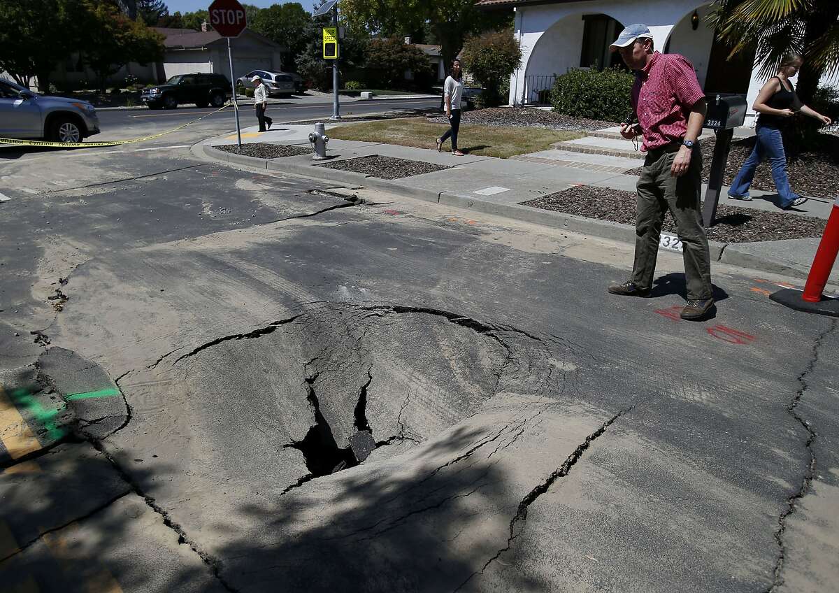 Engineer Justin Moresco (right) of RMS looks over a hole created by the earthquake in Napa, Calif. Risk Management Solutions (RMS) is a group of professionals that look at structural damage, liquefaction zones and interviews to determine the cost of the damage from an earthquake like the South Napa event.