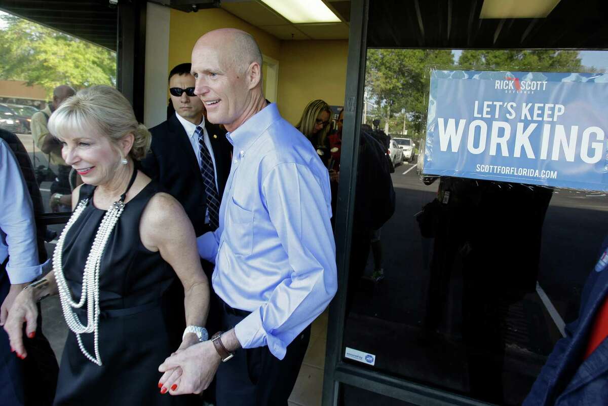 Florida Gov. Rick Scott, right, and his wife Ann, depart after a visit to a phone bank field office thanking volunteers for their work and support, Tuesday, Aug. 26, 2014, in Orlando, Fla. Scott is seeking re-election for a second term as Florida's governor. (AP Photo/John Raoux)
