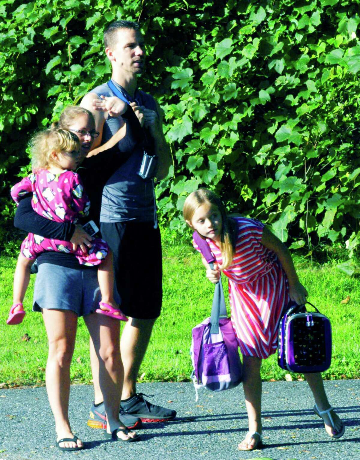 Erinn Williams, 9, a fourth-grader at Sarah Noble Intermeidate School, leans to spot the approach of her school bus on the first day of school in New Milford. There to see her safely off on her educational adventure are her parents, Adriene and Rob Williams, and her younger sister, Mattelyn, 3. Sister Regan, 7, had just boarded her bus to Hill and Plain School.