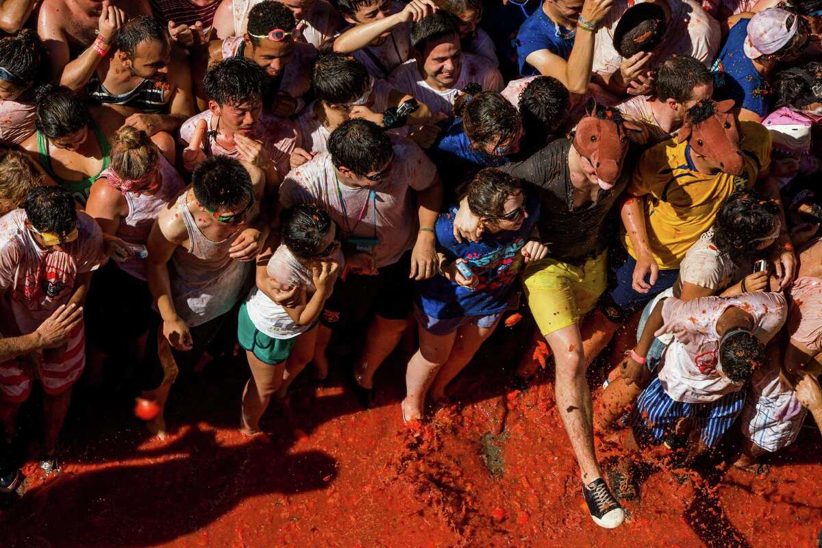 Revellers take part in the annual "tomatina" festivities in the village of Bunol, near Valencia on August 27, 2013. Some 22,000 revellers hurled 130 tonnes of squashed tomatoes at each other drenching the streets in red in a gigantic Spanish food fight known as the Tomatina.
