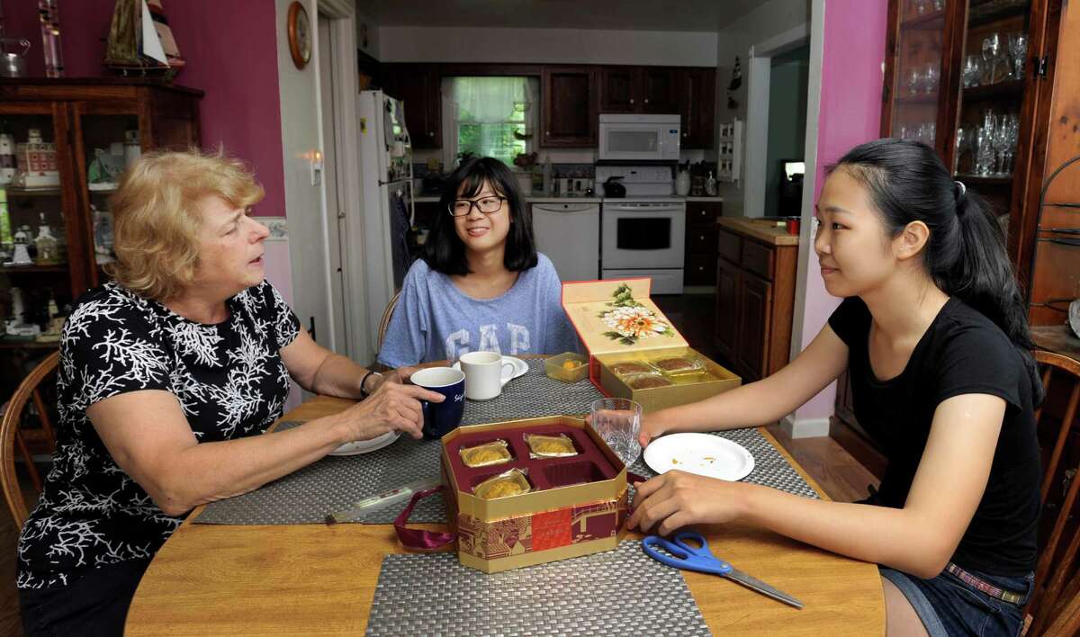 Ginny Schmidt-Gedney, left, has opened up her Danbury home to two exchange students from China. Center is Victoria Li, 13. Right is Lily Duan, 16. The girls are students at Immaculate High School in Danbury, Conn. Wed. Aug. 27, 2014.