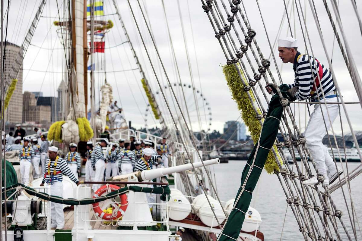 Sailors decked out in blue and white stripes prep the Mexican navy tall ship Cuauhtémoc for the dock after arriving in Seattle.