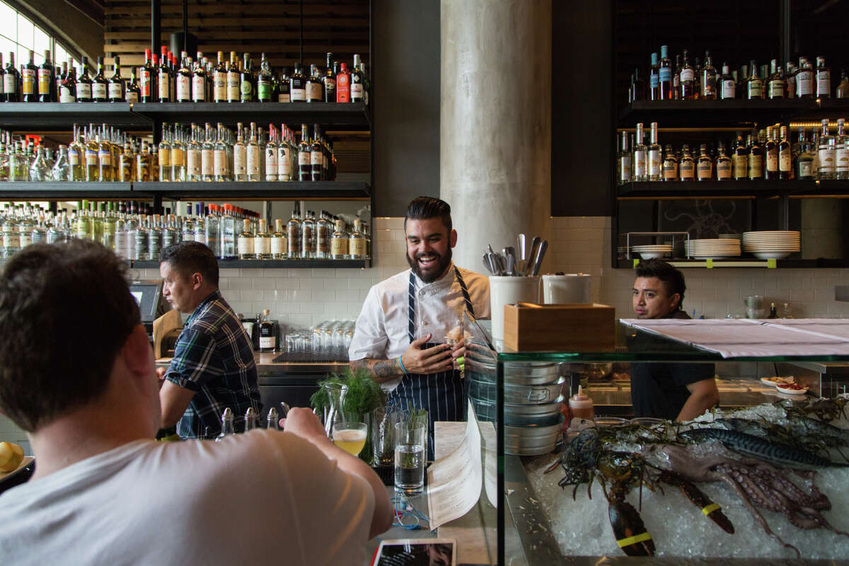 Sous chef Joey Malim mingles with patrons at the bar while shucking oysters at the raw bar at Jack's Oyster Bar and Fish House in Oakland.