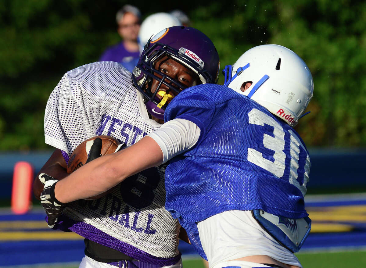 Westhill's Josh Exantus, left, is tackled by Newtown's Nick Samuelson, during football scrimage action in Newtown, Conn. Friday, Aug. 29, 2014.