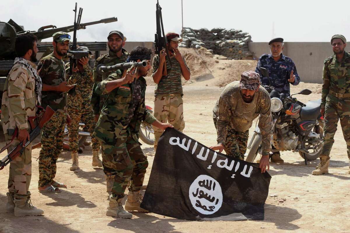 Iraqi security forces hold a flag of the Islamic State group they captured during an operation outside Amirli, some 105 miles (170 kilometers) north of Baghdad, Iraq, Monday, Sept. 1, 2014. Aid began flowing into the small northern Shiite town in Iraq on Monday, a day after security forces backed by Iran-allied Shiite militias and U.S. airstrikes broke a two-month siege by insurgents in a rare victory by government forces.