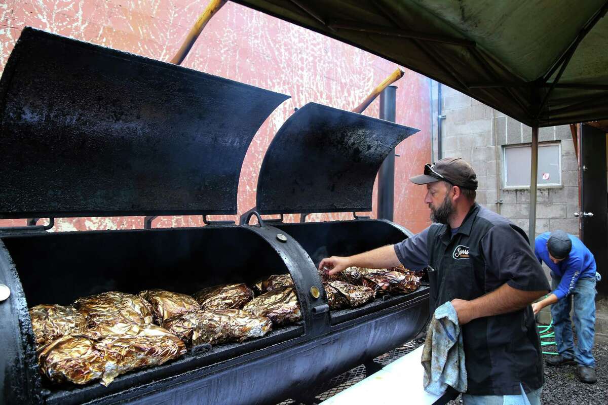 Loal Stahlnecker checks on the meat in the smoker at Storrs Smokehouse in Newberg, Ore.