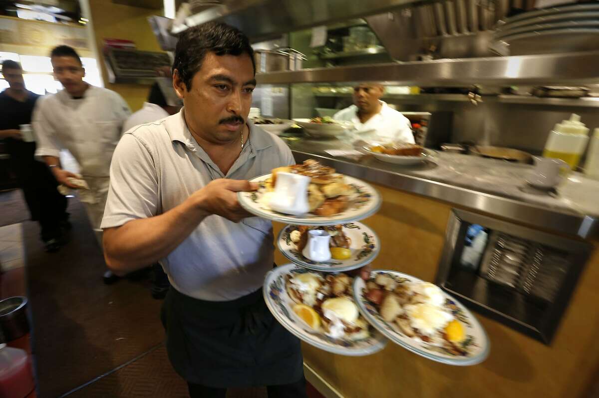 Waiter Jose Beltran picks up an order from the kitchen at Zazie restaurant, in San Francisco, Calif., on Wednesday Aug. 27, 2014. Jen Piallat owner of Zazie offers her employees fixed schedules, full benefits and matching 401k plans and she says her business is more successful for it.