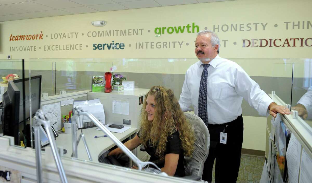 Mark Pragano, customer service manager and Erica Francisco, assistant manager, work together helping a caller, Thursday, Sept. 4, 2014, at the Union Savings Bank in New Milford, Conn.