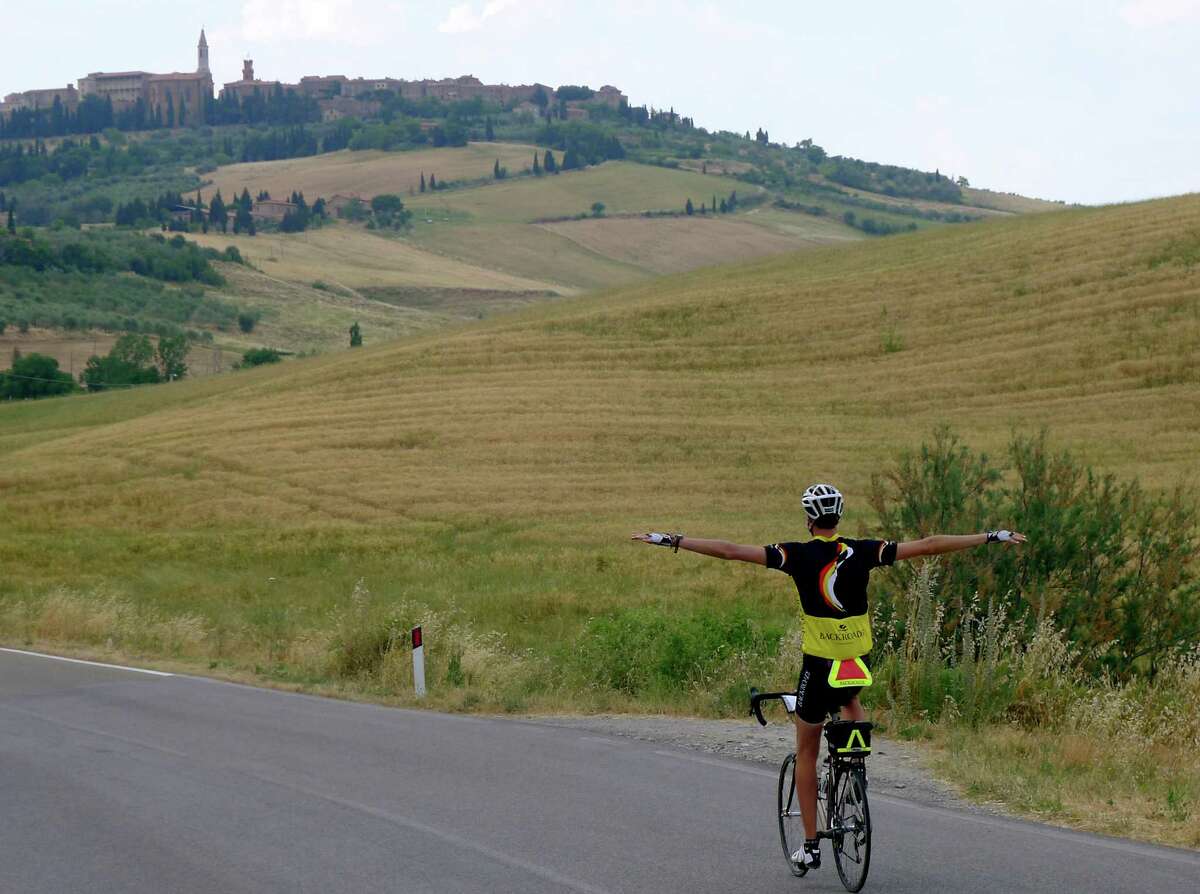 Tour guide Fabio spreading his wings on the road from Albergo Le Terme to Pienza. The town of Pienza is seen in the distance.