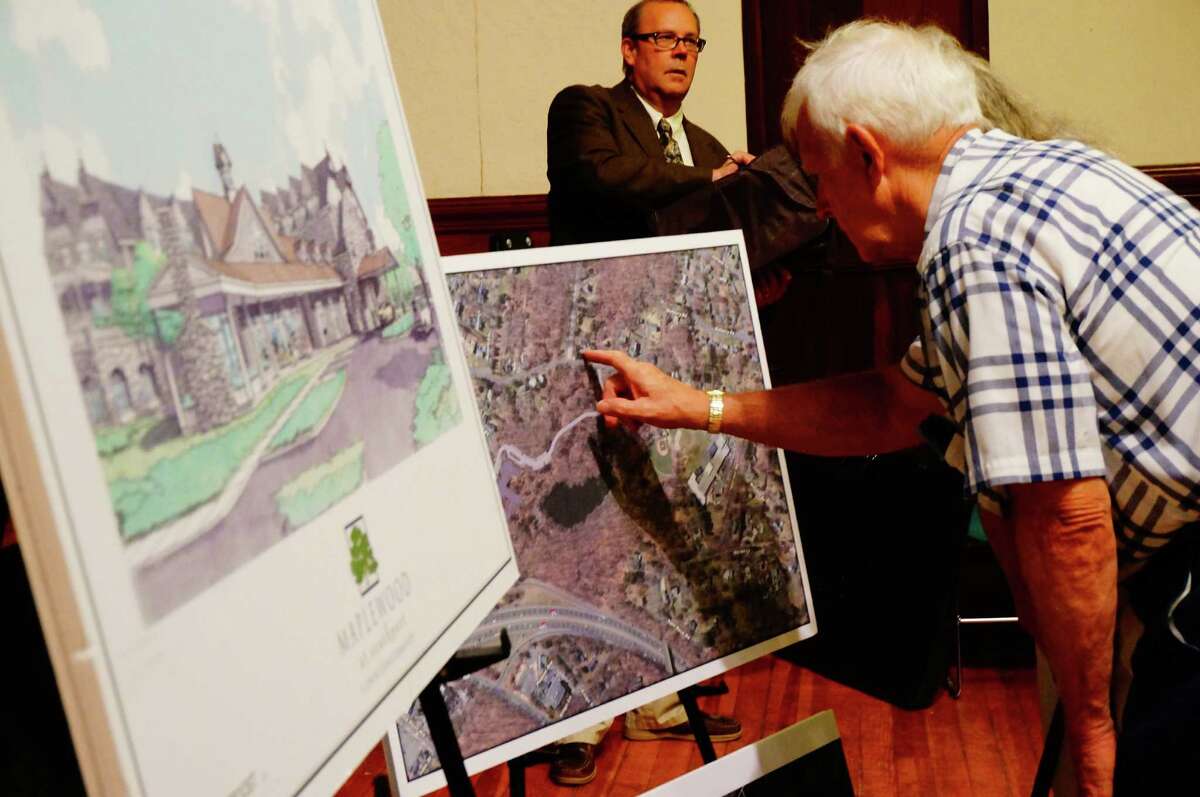 Residents look over the plans for a proposed assisted living facility on Mill Hill Terrace at a meeting for neighbors Thursday.