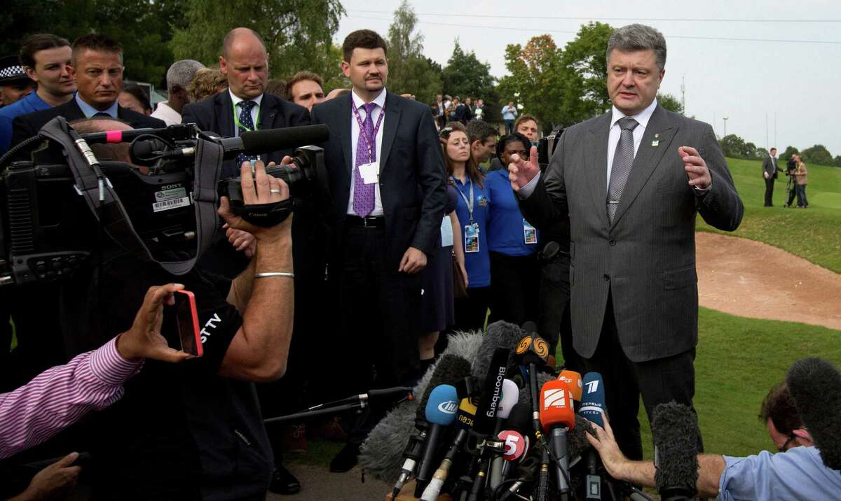 Ukrainian President Petro Poroshenko, center, speaks with the media during a NATO summit at the Celtic Manor Resort in Newport, Wales on Friday, Sept. 5, 2014. The Ukrainian government and pro-Russia rebels have signed a truce deal to end almost five months of fighting. (AP Photo/Virginia Mayo)