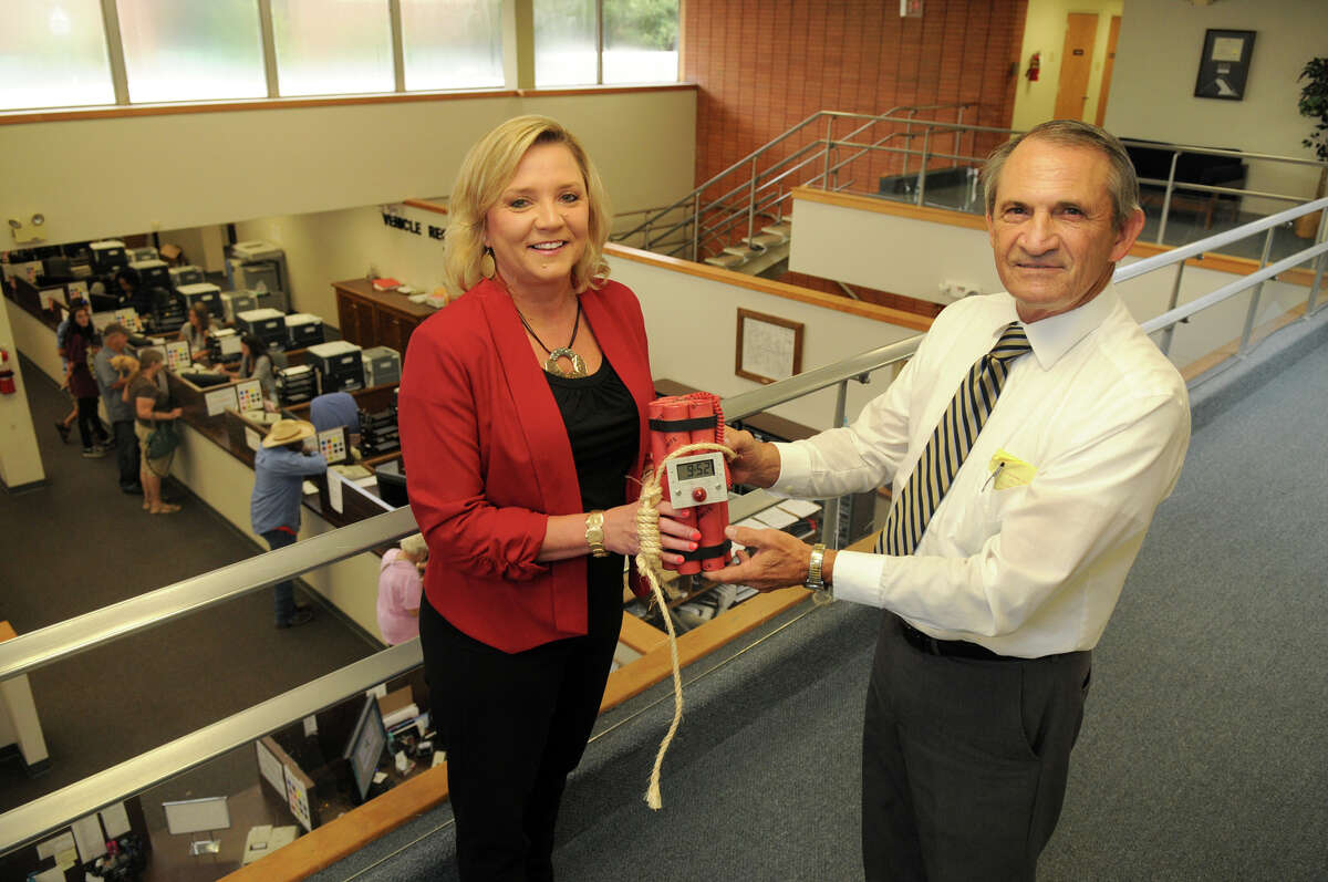 J.R. Moore will be retiring as Montgomery County tax assessor-collector, symbolically handing over the job's responsibilities to chief deputy Tammy McRae, left, along with the novelty "dynamite" clock he was given when he took over the office almost 28 years ago.