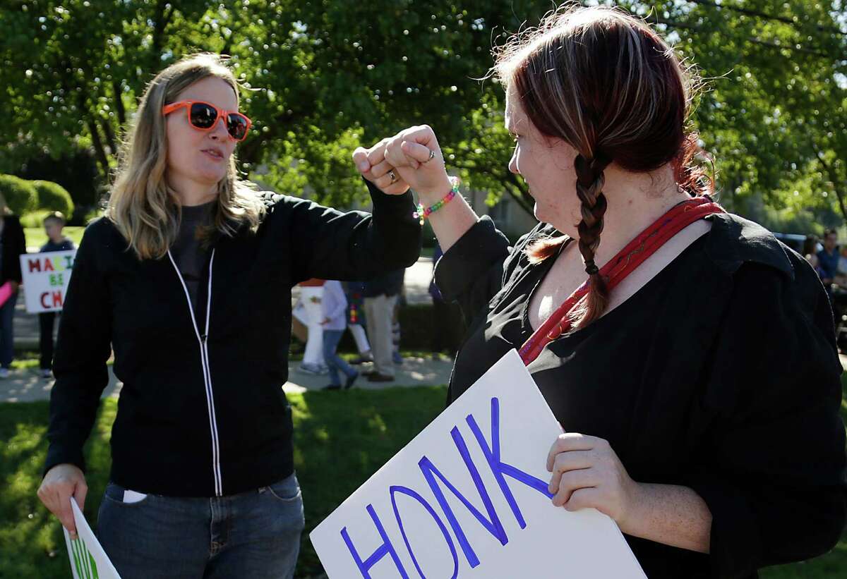 Barbara Webb, 33, of Madison Heights, left, gets a bump from her long time friend Lauren Lennon, 31, of Fraser during a protest on behalf of Webb Sunday Sep. 7, 2014. Webb was fired from Marian High School after administrators at the Catholic all-girl high school were made aware of her nontraditional pregnancy.