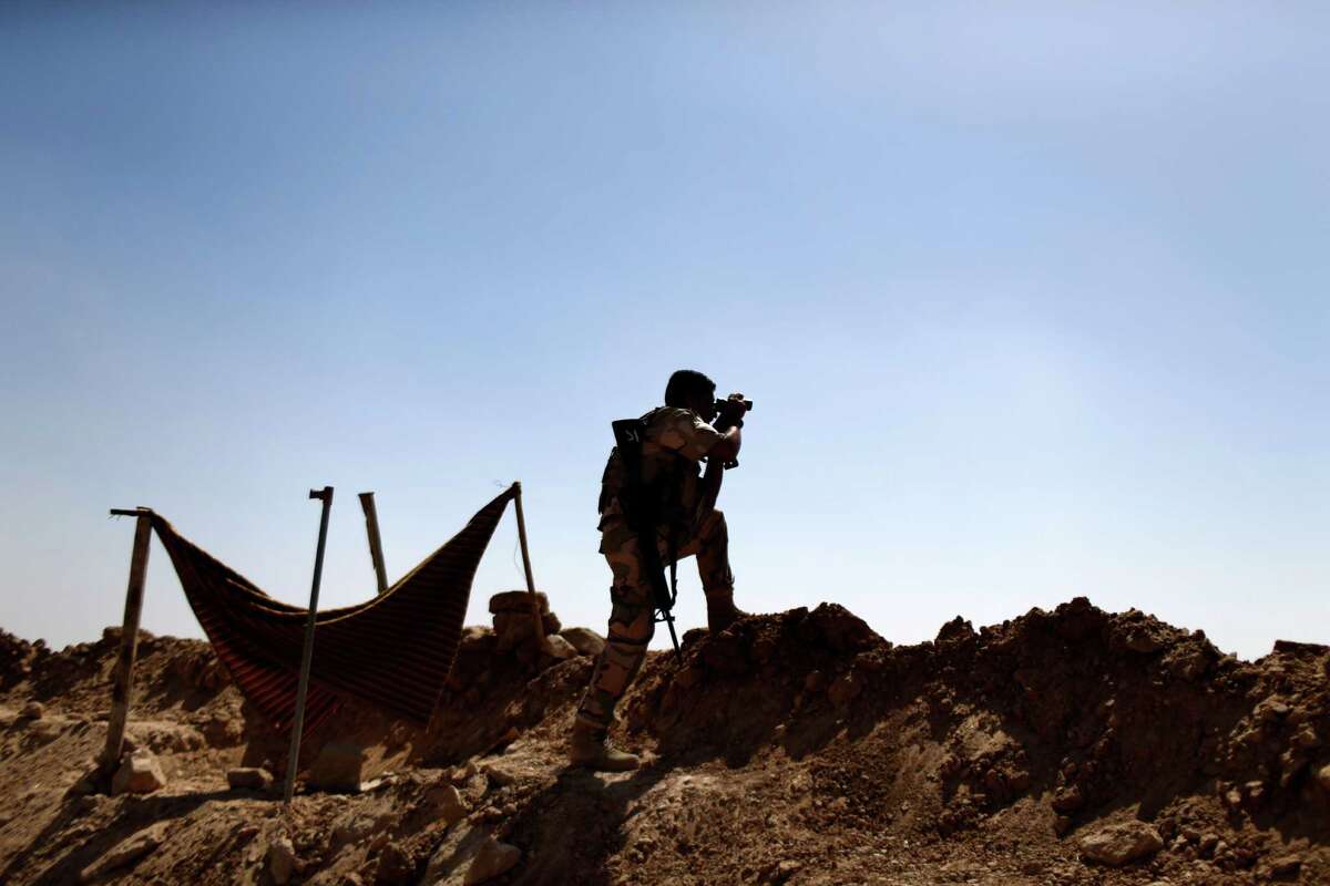 A Kurdish Peshmerga fighter uses binoculars to check on Islamic State group's positions on the outskirts of Makhmour, 300 kilometers (186 miles) north of Baghdad, Iraq, Saturday, Sept. 6, 2014. The U.S. and nine key allies agreed Friday that the Islamic State group is a significant threat to NATO countries and that they will take on the militants by squeezing their financial resources and going after them with military might. (AP Photo/ Marko Drobnjakovic)