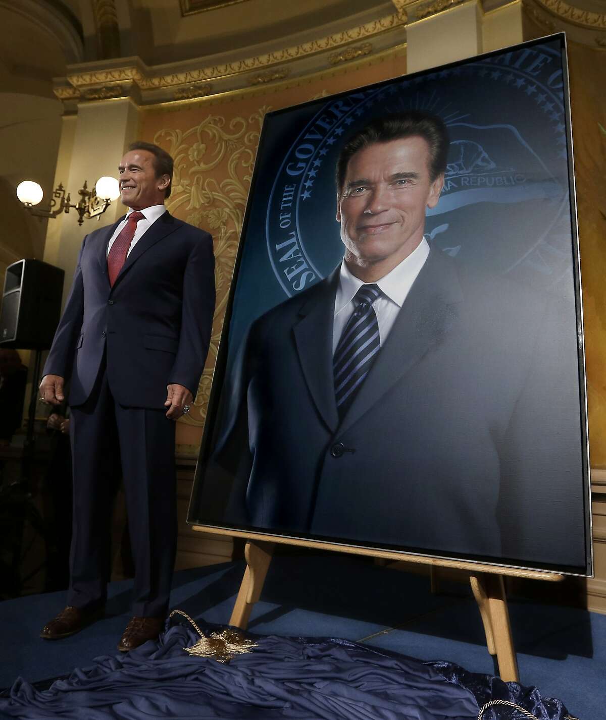 Former Gov. Arnold Schwarzenegger unveil's his official portrait during ceremonies at the Capitol in Sacramento, Calif., Monday, Sept. 8, 2014. The photograph-like giant image of the former governor was done by Austrian artist Gottfried Helnwein and will hang on the third floor of the Capitol. (AP Photo/Rich Pedroncelli)