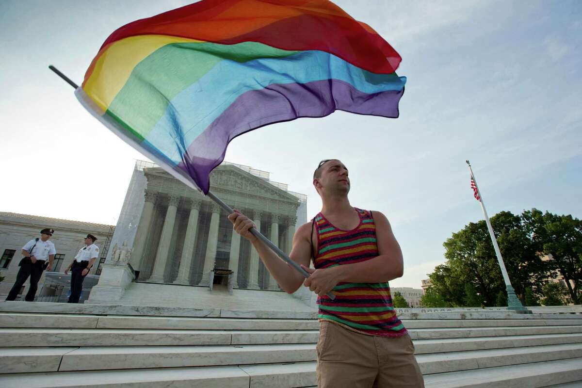 FILE- In this June 26, 2013 file photo, gay rights advocate Vin Testa waves a rainbow flag in front of the Supreme Court in Washington. Both sides in the gay marriage debate agree on one thing: Itâs time for the Supreme Court to settle the matter. Even a justice said recently that she thinks so, too. That emerging consensus makes it likely that the justices soon will agree to take up the question of whether the Constitution forbids states from defining marriage as the union of a man and a woman. While a final ruling isnât likely before June of next year, a decision to get involved could come as soon as the end of this month. (AP Photo/J. Scott Applewhite, File)