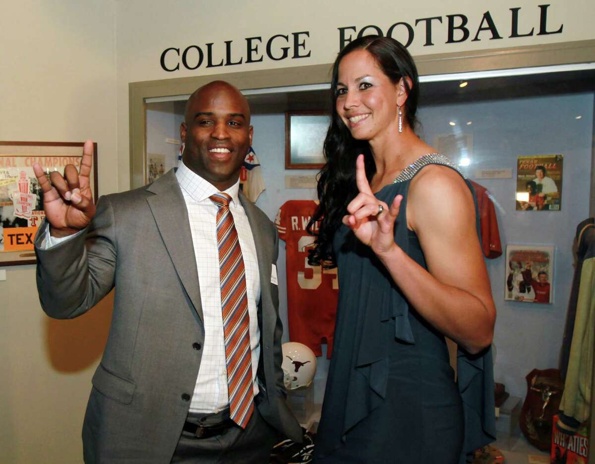 Former Texas football player and Heisman winner Ricky Williams left, and Texas softball pitcher Cat Osterman, right, give the "hook 'em horns" Texas mascot sign at a reception before the induction for the 2013 class of the Texas Sports Hall of Fame.