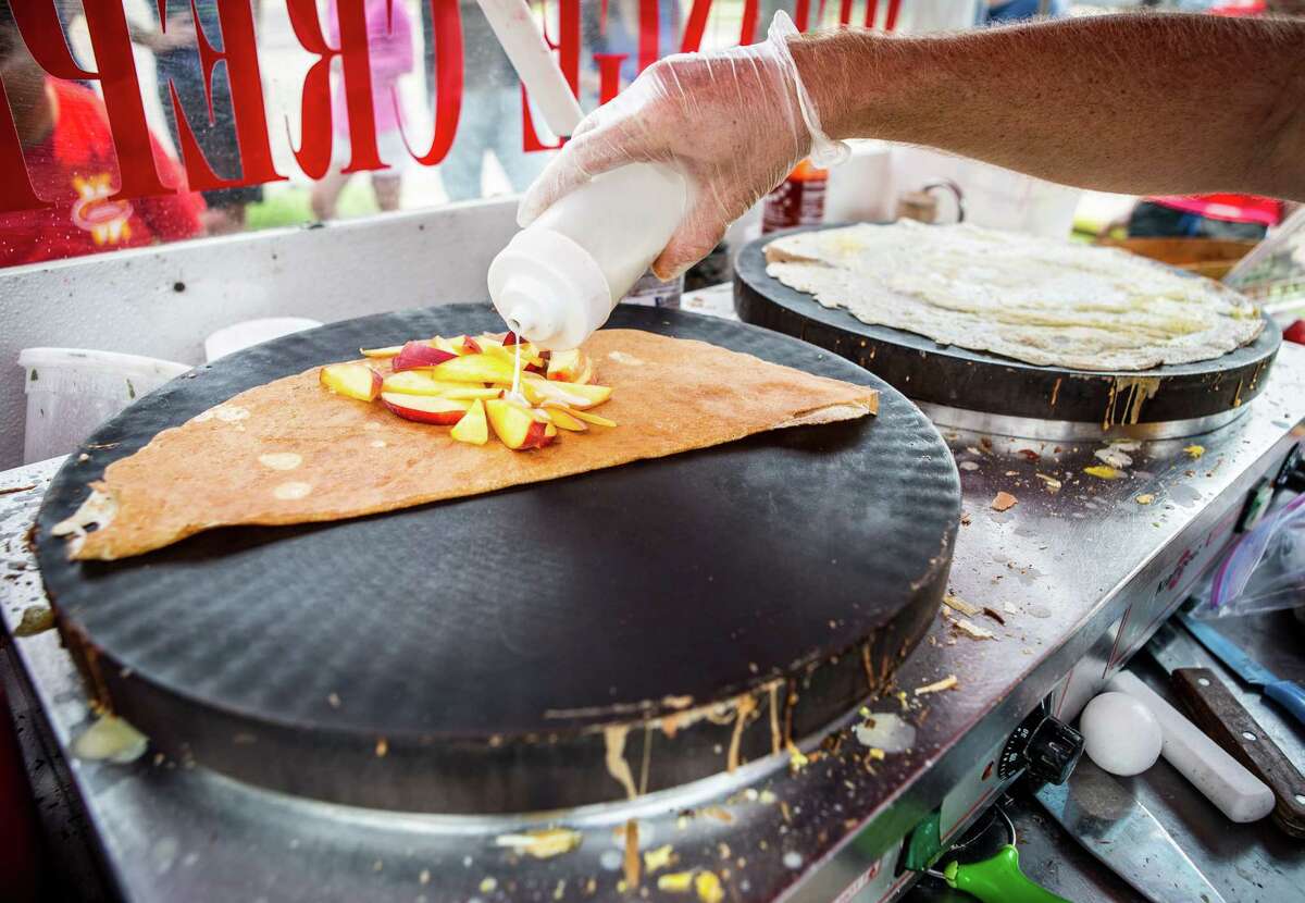 Sean Carroll, owner of Melange Creperie, puts cream on fresh nectarines as he fills an order with his two crepe hot plates, photographed, Sunday, July 20, 2014, in Houston. ( Nick de la Torre )