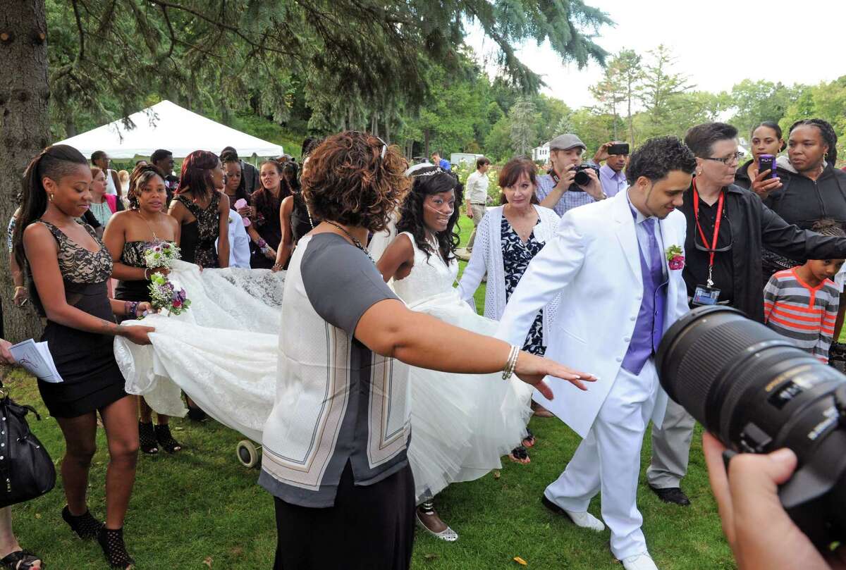 Bride Jahaysia Graham, center, and groom Jathyis Lajuett, right, walk through the crowd after being married at the Central Park Rose Garden Friday afternoon, Sept. 12, 2014, in Schenectady, N.Y. (Michael P. Farrell/Times Union)
