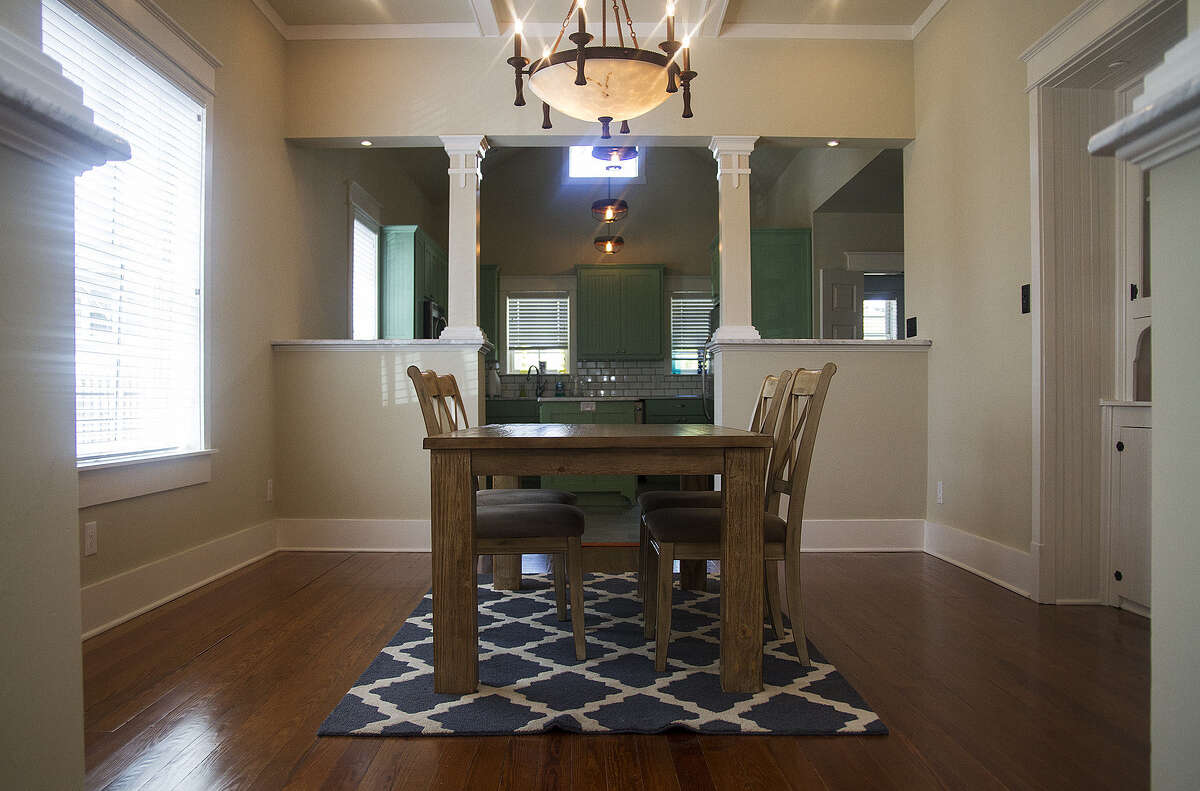 It took Cody Doege and Chad Walling three years to renovate this Tobin Hill home. They kept the original pine floors, seen here in the dining room. A trio of pendant light fixtures in the kitchen (background) are made from metal chicken feeders.