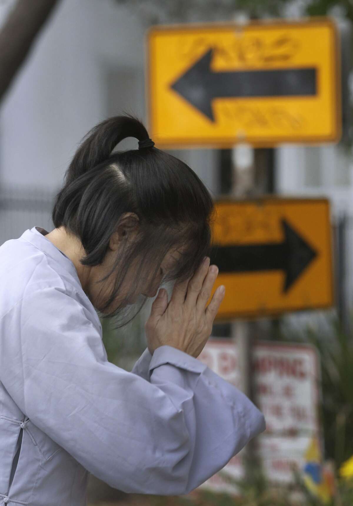 Vina Vo prays at sunrise in front of a Buddhist altar erected at 11th Avenue and East 19th Street in Oakland, Calif. on Saturday, Sept. 13, 2014.