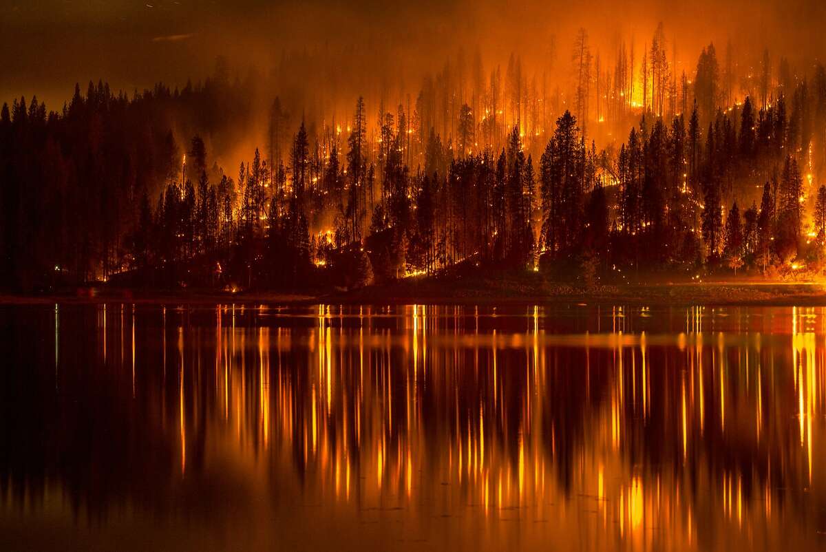 This Sunday, Sept. 14, 2014 photo shows fire as it approaches the shore of Bass Lake, Calif. Crews are attempting to get better access to two raging wildfires in California Monday that have forced hundreds to evacuate their homes. 