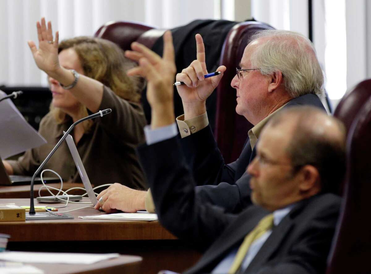 State Board of Education board members, from left, Donna Bahorich, David Bradley, and Thomas Ratliff, raise their hands to ask questions during a public hearing for new textbooks up for adoption and use in classrooms statewide, Tuesday, Sept. 16, 2014, in Austin, Texas. The Texas Board of Education is considering 104 proposed social studies, history, geography and government textbooks that publishers have submitted for approval and use in public schools statewide. (AP Photo/Eric Gay)