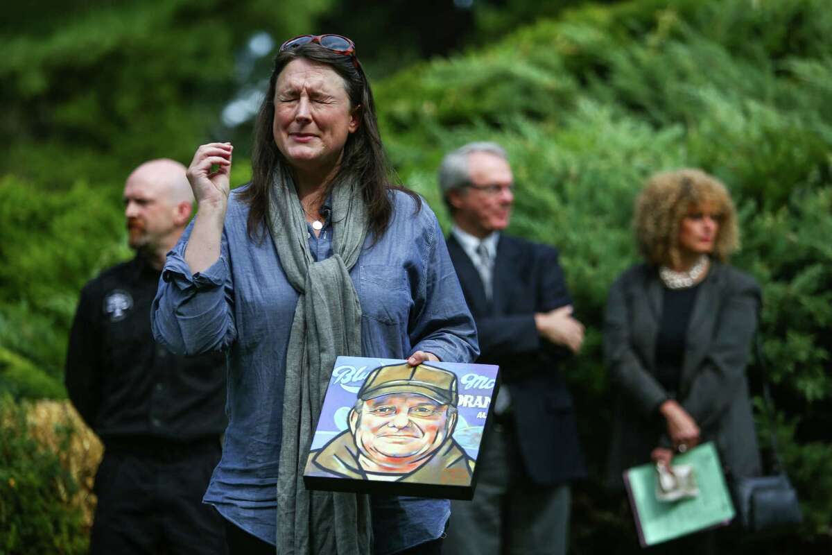 Mary Larson, a nurse at Harborview Medical Center's Pioneer Square Clinic, recalls a story about Gary Campbell as she holds a painting she made of him during a burial ceremony for the remains of 137 unclaimed or indigent people on Wednesday, September 17, 2014 in Renton.