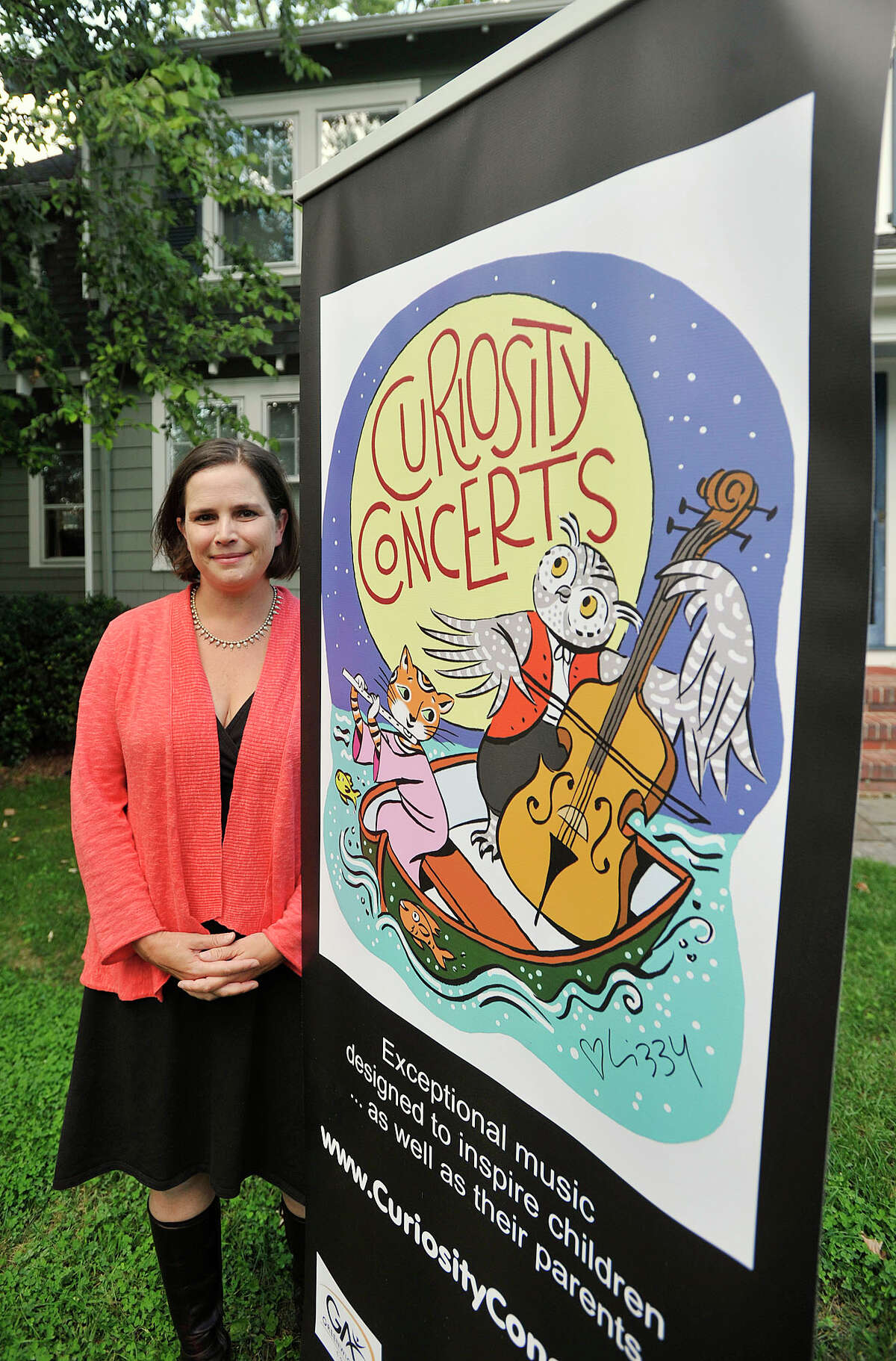 Shelly Cryer poses next to a banner displaying Curiosity Concerts in her front yard in Old Greenwich, Conn., on Thursday, Sept. 18, 2014. Shelly is the daughter-in-law of world famoous violinist Isaac Stern and is the producer of Curiosity Concerts, a free family concert she started in Greenwich.