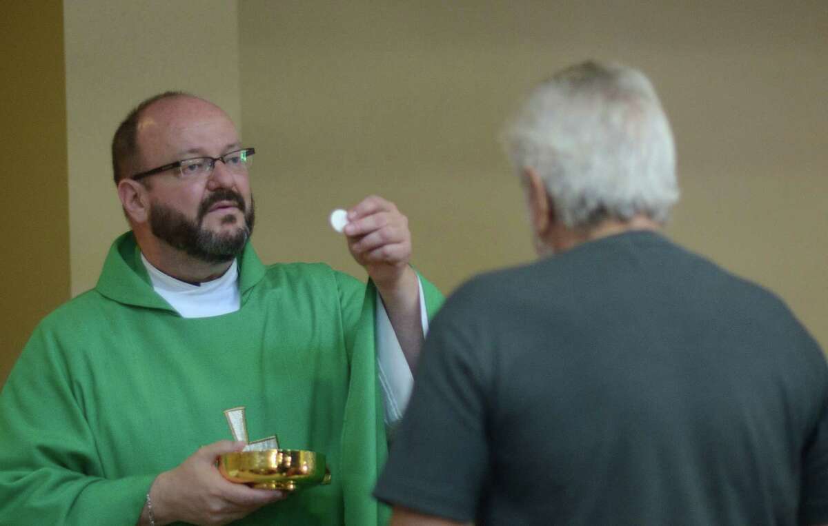 Father Kevin Fausz, the new pastor of Our Lady of Perpetual Help Catholic Church on Grimes Street in the East Side, gives Holy Communion on Tuesday, Aug. 5, 2014.