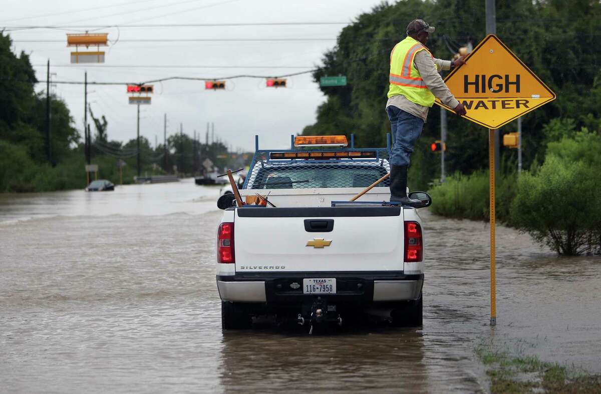 A city worker switches the sign to warning motorist of high water in the area, near the intersection of Greenhouse Road and Saums Road, where several cars stalled earlier in the day on Friday, Sept. 19, 2014, in Katy. Heavy rains cause South Mayde Creek to overflow from its banks and flood the surrounding area.
