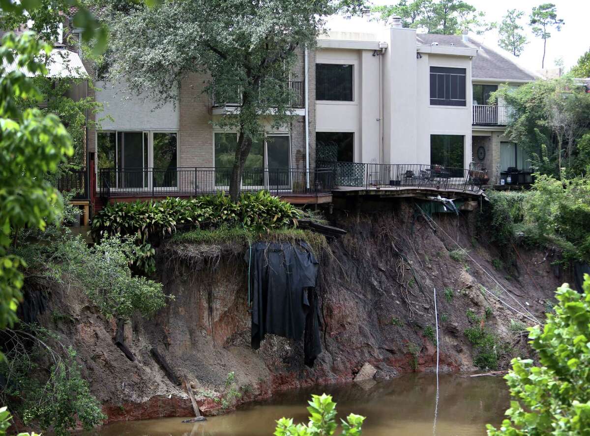 A water hose dangles from one of the Memorial Woods Town Homes after a part of the property collapses into the Spring Branch Bayou due to heavy rains and erosion on Friday, Sept. 19, 2014, in Houston.