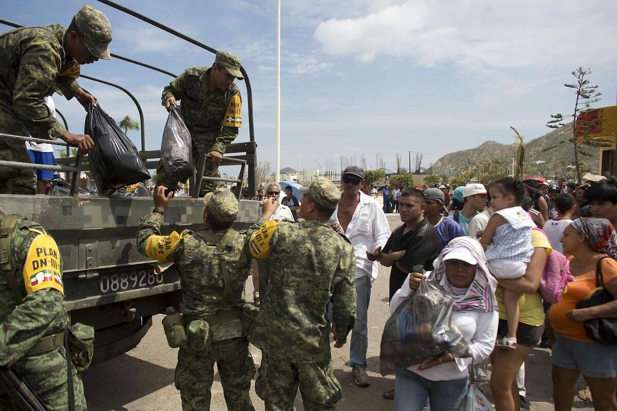 Soldiers distribute food and water to people outside the local Red Cross in the city of Cabo San Lucas, Mexico, Friday, Sept. 19, 2014. Most commerce in the city has halted after power and other utilities were knocked off by hurricane Odile. (AP Photo/Dario Lopez-Mills)