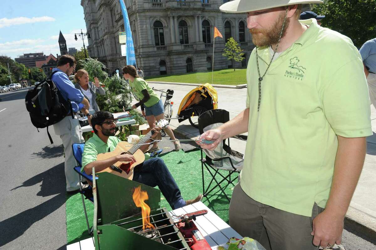 Drew Pollak-Bruce, right, with Parks & Trails New York roasts a marshmallow as part of Park(ing) Day in paid a parking spot on Washington Avenue on Friday Sept. 19, 2014 in Albany, N.Y. (Michael P. Farrell/Times Union)