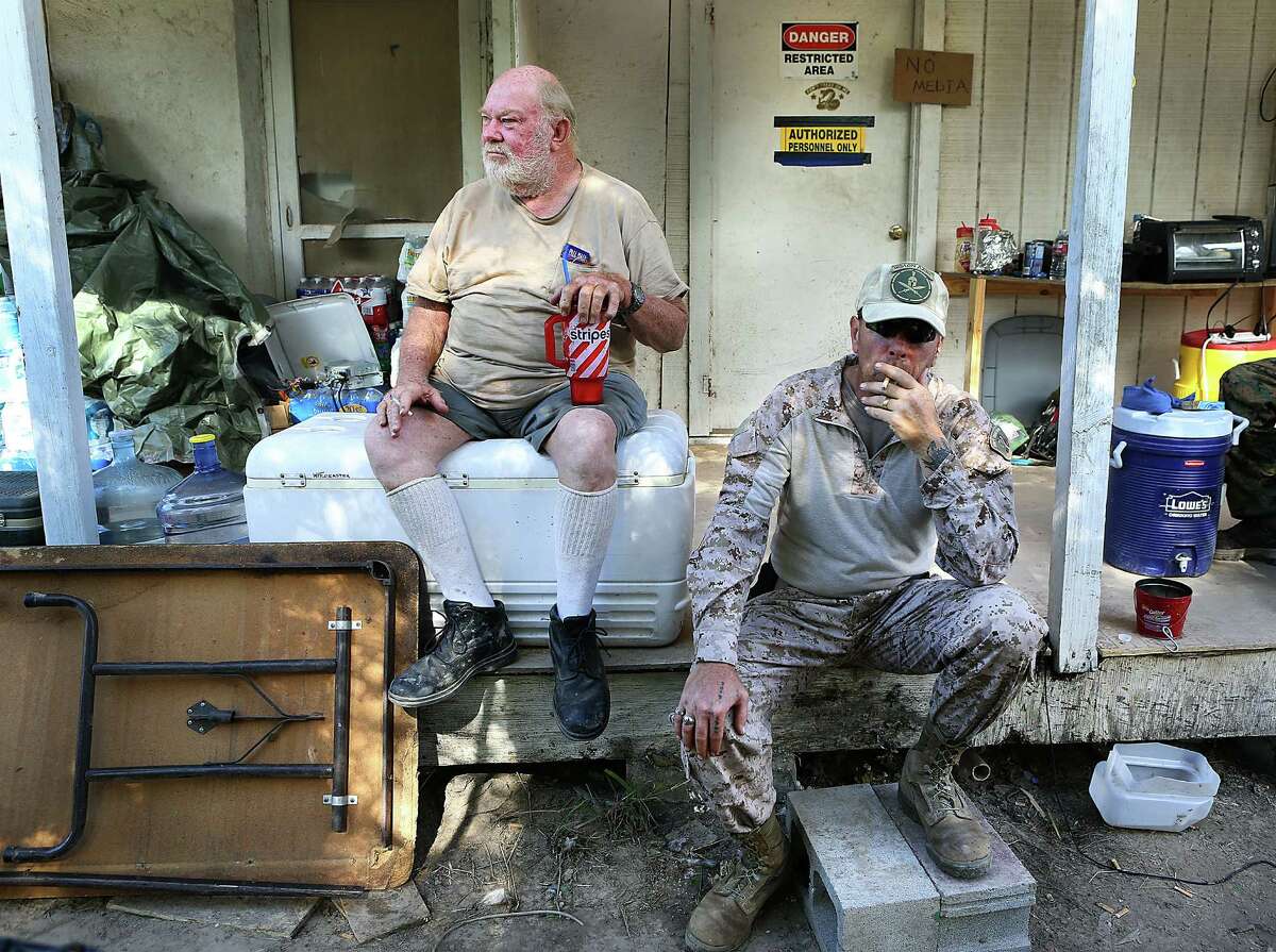 Landowner Cuban “Rusty” Monsees sits with the cigarette-smoking KC Massey. Monsees invited the armed civilians who call themselves “American Patriots” onto his property along the Rio Grande.
