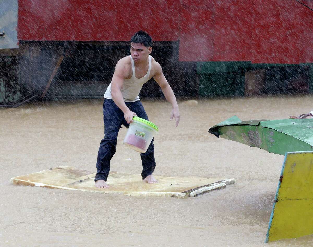 A resident balances himself on a makeshift floater as he evacuates to safety after heavy monsoon rains spawned by tropical storm Fung-Wong flooded Marikina city, east of Manila, Philippines and most parts of the metropolis Friday, Sept.19, 2014. Heavy rains due to a storm and the seasonal monsoon caused widespread flooding Friday in the Philippine capital and nearby provinces, shutting down schools and government offices.