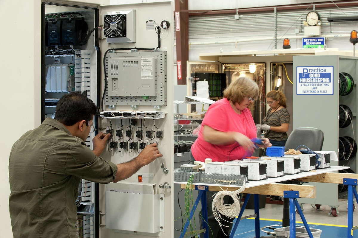 Workers assemble a control panel at Dresser-Rand.