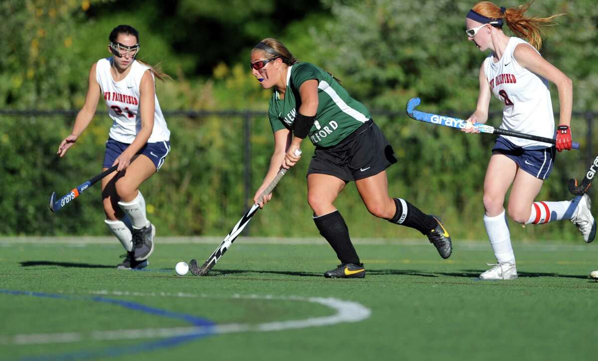 New Milford's Lindsey Heaton drives to the goal between two New Fairfield players during their field hockey match Tuesday, Sept. 23, 2014, at New Fairfield High School.