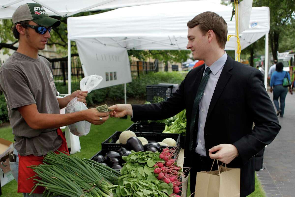 Andrew Brown purchases radishes from Adtinson Farms during the City Hall Farmers Market on Wednesday, Sept. 24, 2014, in Houston. The City Hall Farmers Market has re-opened for its 9th season, and hosted by Urban Harvest. Approximately 30 vendors, such as local farmers, pre-prepared foods, food trucks, are present from 11-1:30 p.m. every Wednesday.