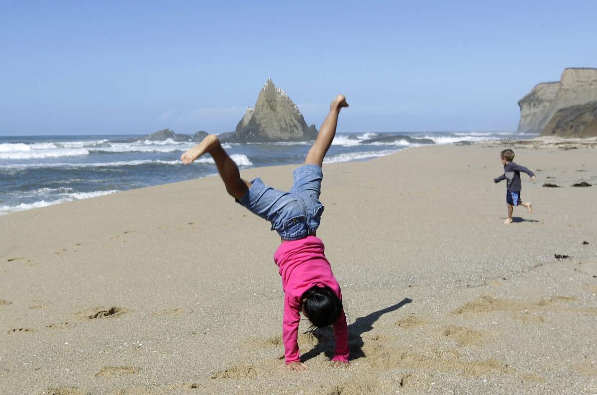 An Na Toth, 9, performs a cartwheel while visiting Martin's Beach with her brother Henry (right), 6, in Half Moon Bay, Calif. on Thursday, Sept. 25, 2014, one day after a judge ordered landowner Vinod Khosla to unlock a private gate and allow public access to the beach. Public access has been spotty since then.