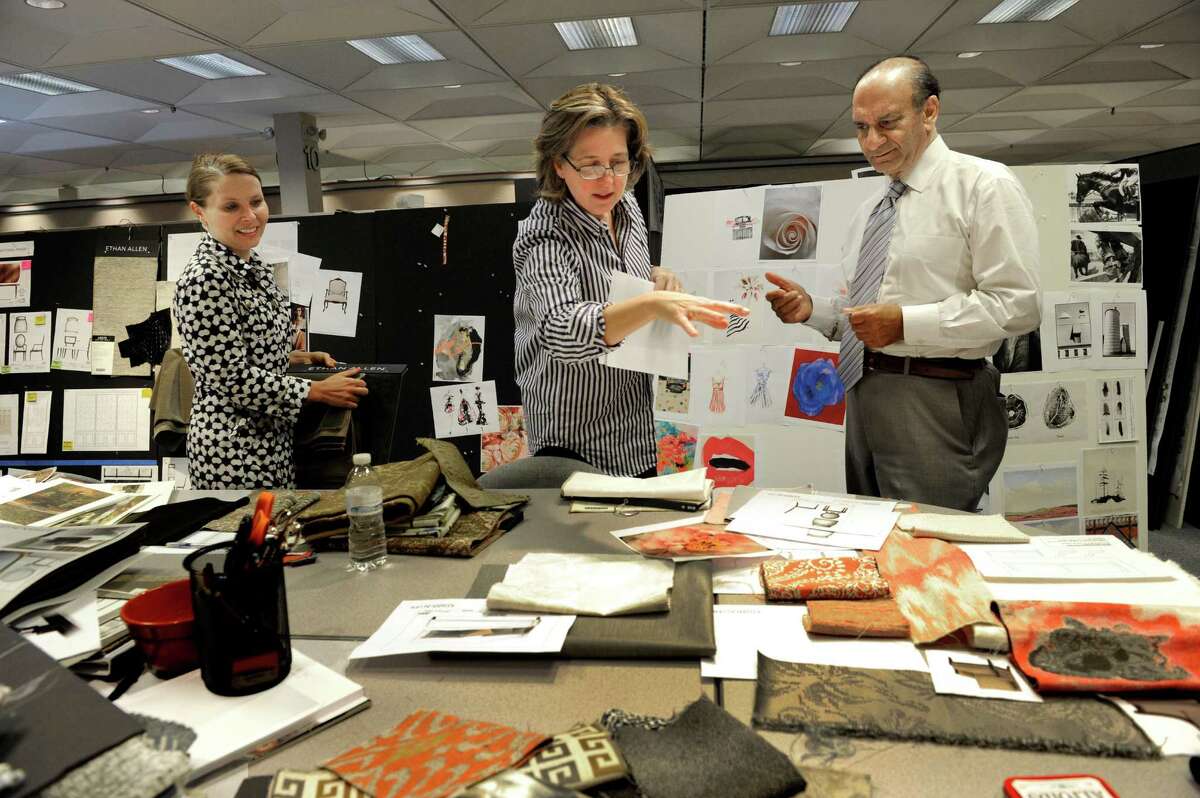 Farooq Kathwari, the CEO of Ethan Allen Interiors, right, visits the display planning department at the company headquarters on Mill Plain Road in Danbury, Conn., Thursday, Sept. 25, 2014. Left is Anne Lekow. Center is Nora Murphy, a style advisor.