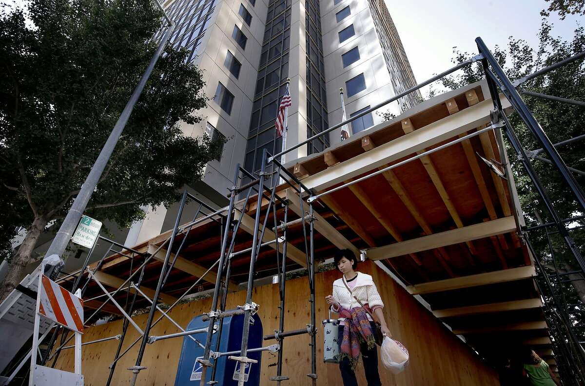 The exterior has been surrounded by roofed scaffolding to protect pedestrians in case any more window fall from above, which has happened in the past at the California State Board of Equalization Board headquarters building in downtown Sacramento, Calif., as seen on Friday Sept. 26, 2014. The California State Board of Equalization headquarters in down town Sacramento has a long history of problems since the high rise was built 22 years ago- mold, flooding, fee falling elevators and falling windows to name a few.