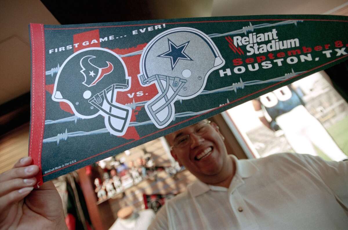 "Go Texan" store employee Larry DeLaCruz show off a pennant, one of many souvenir offerings featuring the Inaugural Texans vs. Cowboys game, at the store at Reliant Stadium, Wednesday afternoon, September 4, 2002. (Smiley N. Pool/Chronicle)