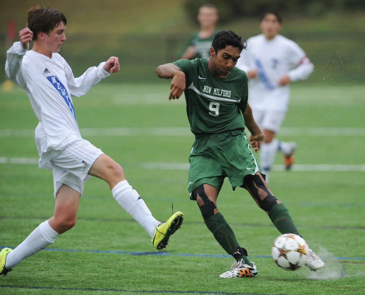 Newtown's Kaj Djonne, left, defends a shot by New Milford's Gyan Kandhari in New Milford's 4-0 win over Newtown in the high school soccer game at Treadwell Town Park in Sandy Hook, Conn. Tuesday, Sept. 30, 2014.