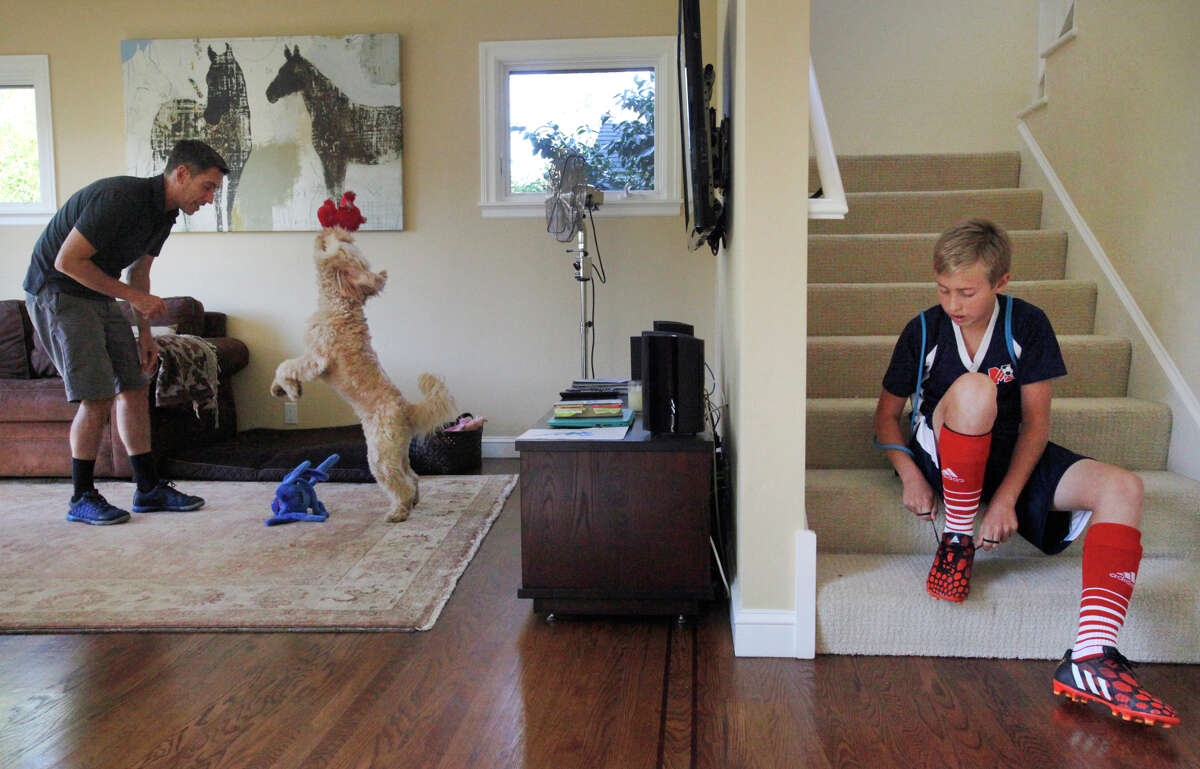 Chris Ford plays with Ozzie as his son Cole, 13, laces up his soccer cleats Sunday in their Mill Valley home.