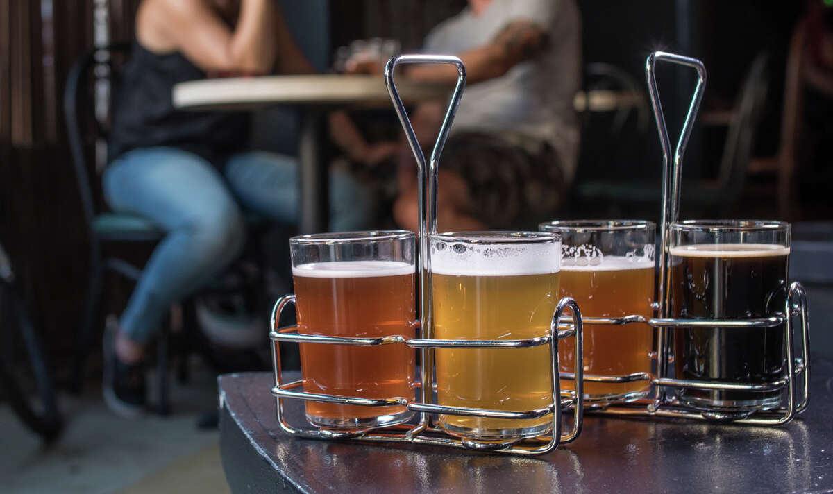 At Woods Bar & Brewery in Oakland, clockwise from top, try a taste sampler for $10, drink up a tall one like Zach Ahern or kick back and appreciate the still-evolving ambience on the outdoor patio, fireplace included.