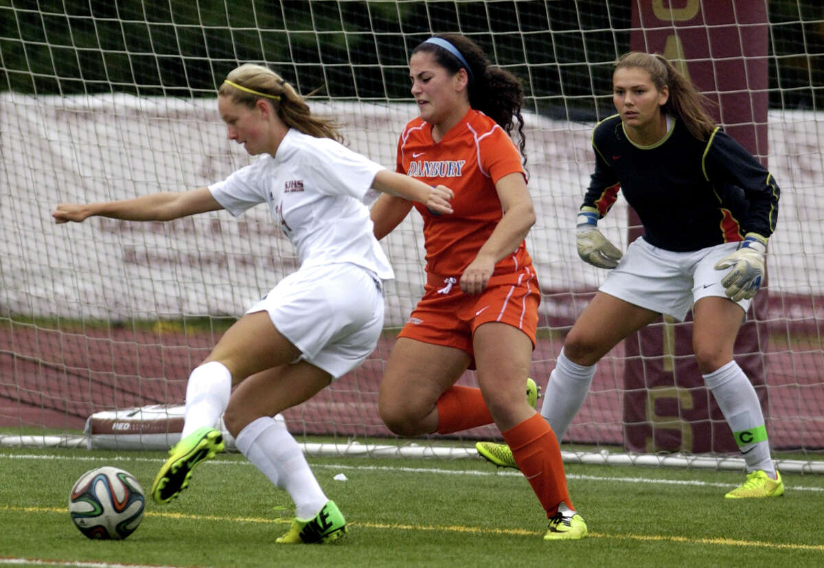 St. Joseph's Lindsey Savko gets this ball past Danbury goalie Allie Smith, at right, to score, during girls soccer action in Trumbull, Conn., on Tuesday Oct. 1, 2014.